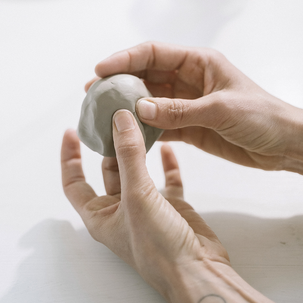 közeli kép kezekről egy darab agyaggal